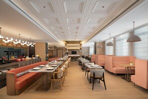 Et moderne restaurantinteriør med et aflangt spiseområde, båse og en bar.