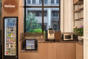 Cozinha moderna com máquina de vendas automática, micro-ondas e cafeteira.
