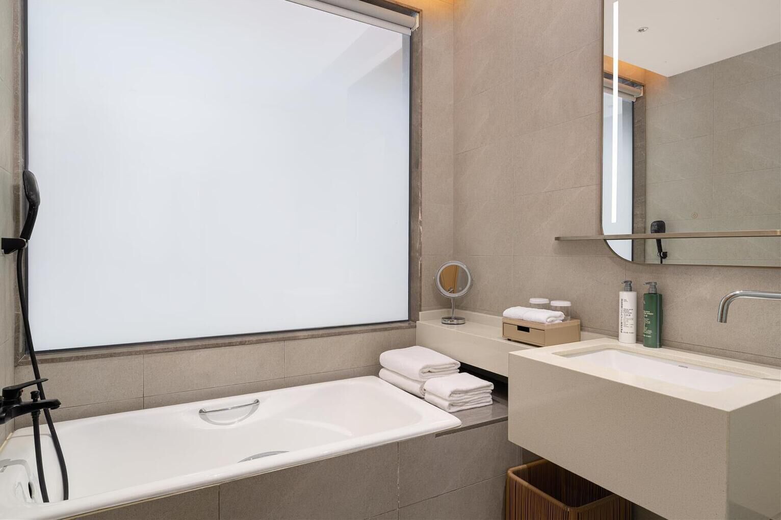 A modern bathroom with a bathtub, two sinks, a vanity, and a mirror.