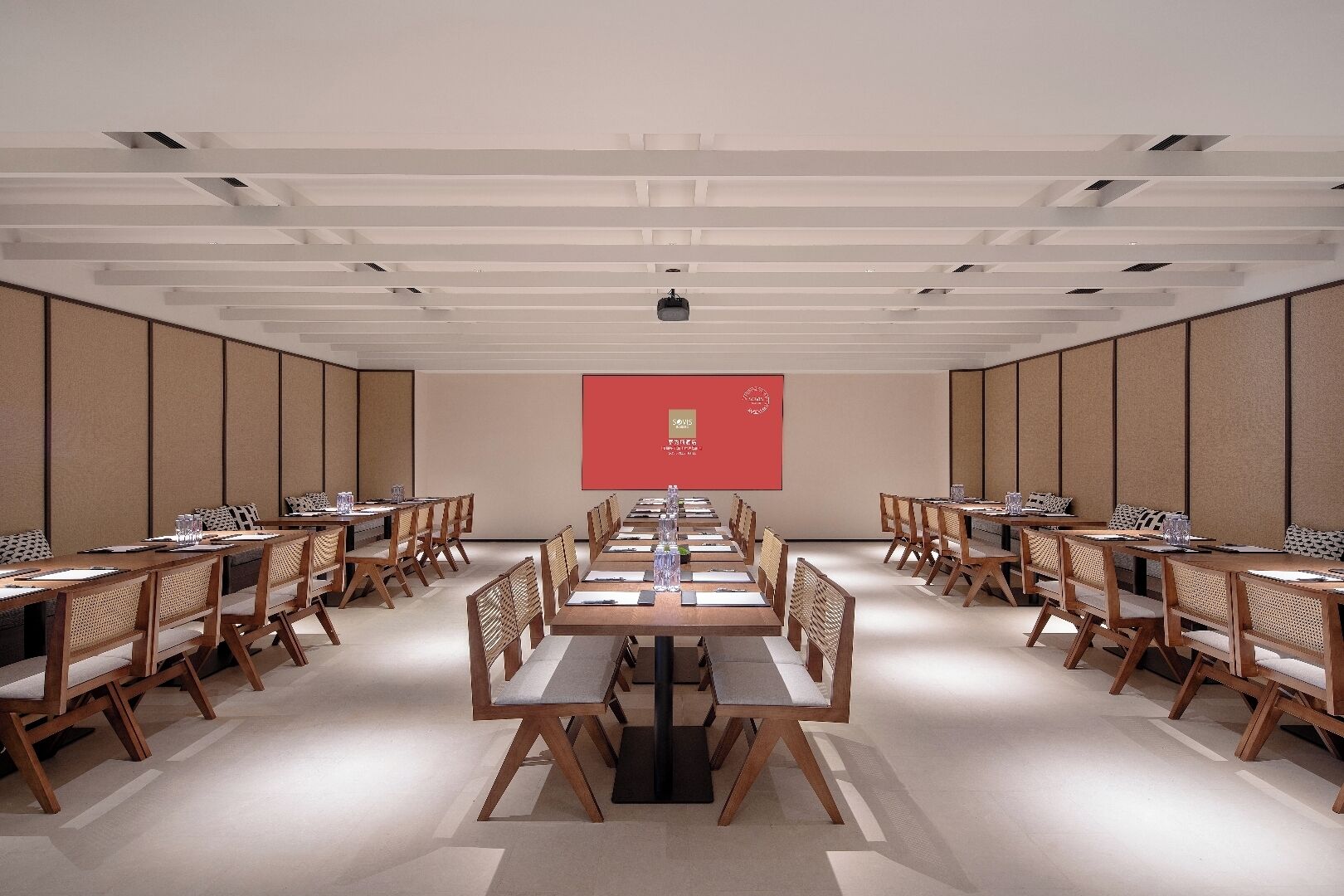 A conference room with long tables, chairs, and a projection screen.