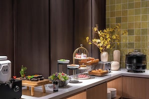 Un buffet proposant divers plats, une machine à café et une plaque de cuisson portable.
