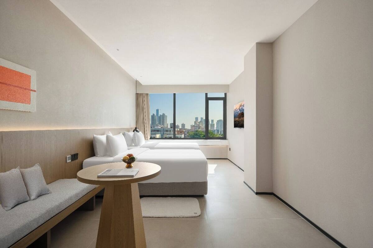 Una habitación de hotel moderna con vista a la ciudad, un sofá, una cama y una mesita.