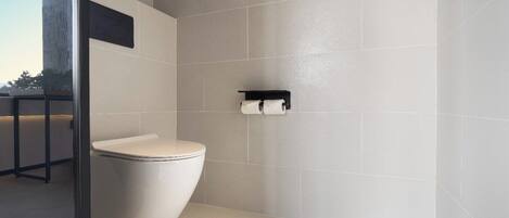 A modern bathroom with a toilet, a towel rack, and a glass partition.