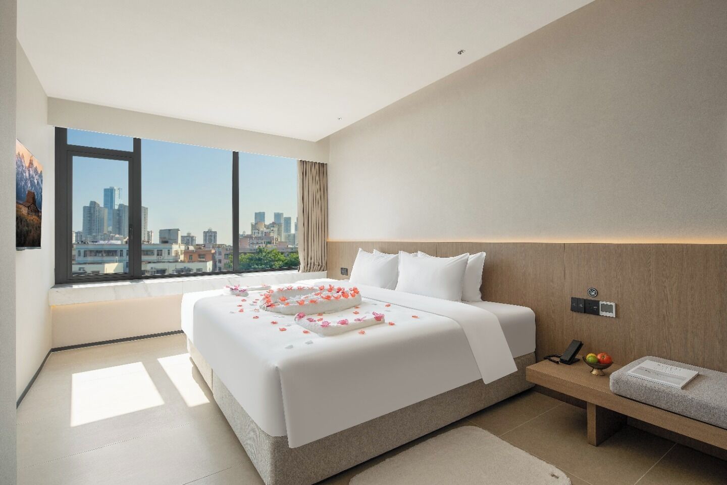 Une chambre d’hôtel moderne avec un grand lit, une table de chevet, une commode et une vue sur le panorama urbain.