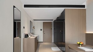 A modern bathroom with a vanity, mirror, and a bowl of fruit on a table. - SOVIS PLUS HOTEL (Shenzhen)