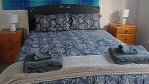Une chambre à coucher avec un lit, deux tables de chevet et une lampe fixée au mur.
