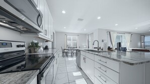Una cocina moderna con estufa integrada, un fregadero y una zona de comedor con sillas.
