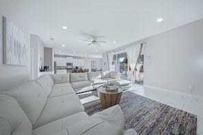 Ein modernes Wohnzimmer mit einer Eckcouch, einem Couchtisch und Blick auf die Küche und den Essbereich.