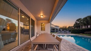 Un espacio al aire libre techado con piscina, una mesa de comedor y sillas.