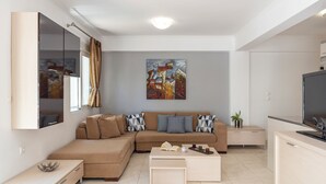 A modern living room with a sectional sofa, a coffee table, a flat-screen TV, and a painting on the wall. - Haven Home: Central & Quiet- Elli Beach & Old Town (Rodos)