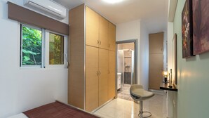A bedroom with a bed, a wardrobe, a bathroom with a shower, and a small sitting area. - Haven Home: Central & Quiet- Elli Beach & Old Town (Rodos)