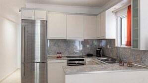 A modern kitchen with a stainless steel refrigerator, a built-in oven, and a granite countertop. - Haven Home: Central & Quiet- Elli Beach & Old Town (Rodos)