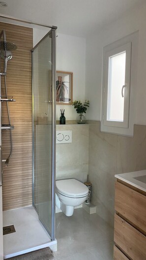 Ein Badezimmer mit Dusche, Toilette und Waschtisch.