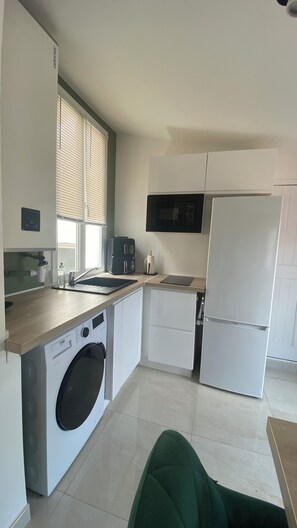 Eine kompakte Küche mit Waschmaschine, Mikrowelle und Kühlschrank.