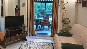 Un salon équipé d’un téléviseur, d’un canapé, d’une table basse et offrant une vue sur une terrasse extérieure.