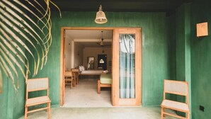 Una habitación con pared verde, un banco de madera, una mesa de comedor con sillas y una lámpara colgante.