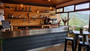 A bar area with wooden shelves, a counter, and a view of the outdoors. - Hotel Le beau Site (Auris)