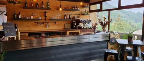Un rincón de bar con estantes de madera, una barra y vistas al exterior.