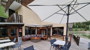 An outdoor patio with tables, chairs, and umbrellas. - Hotel Le beau Site (Auris)