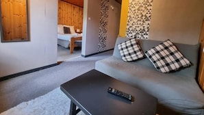 A room with a grey sofa, a black coffee table, and a remote control on it. - Hotel Le beau Site (Auris)