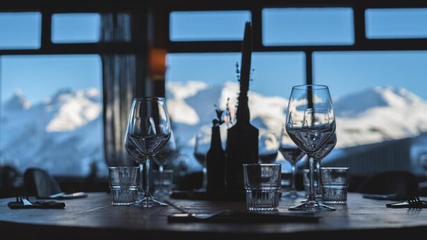 A table set with wine glasses and a bottle, with a mountain view in the background. - Hotel Le beau Site (Auris)