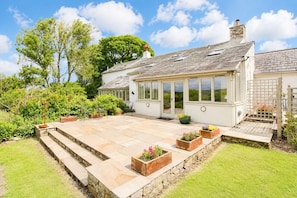 A house with a patio, stone steps, and a conservatory. - Claybottom Farm, Caldbeck - in a rural setting with fell walks from the door (Hesket Newmarket)