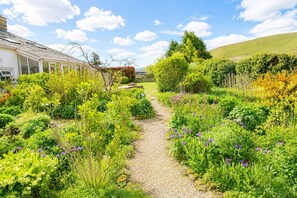 A garden path leading to a house with a sloped roof and large windows. - Claybottom Farm, Caldbeck - in a rural setting with fell walks from the door (Hesket Newmarket)