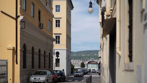 Eine enge Straße, gesäumt von parkenden Autos und Gebäuden.