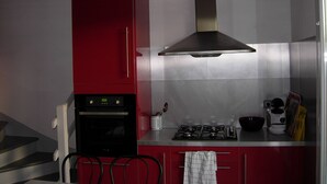 Una cocina con un armario rojo, campana extractora de acero inoxidable y una estufa a gas.