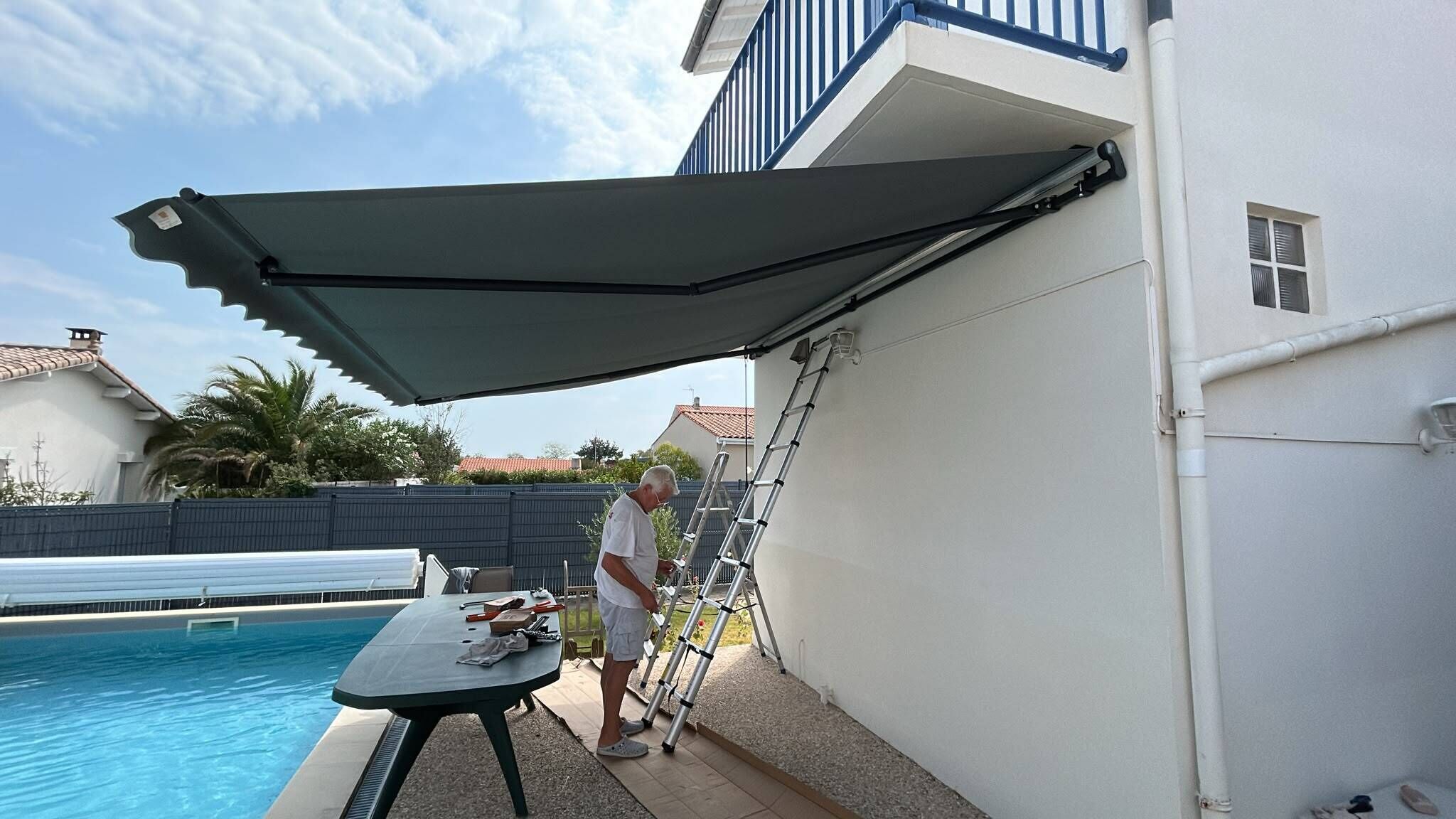 Zona de piscina amb terrassa coberta, una taula amb coses i una escala adossada a la paret.