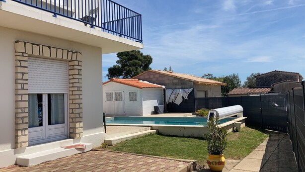 Una propiedad residencial con piscina, terraza cubierta y patio cercado.