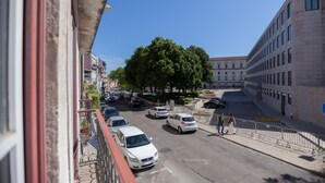 Vista de la calle con coches aparcados, arbolado y un edificio de fachada moderna.