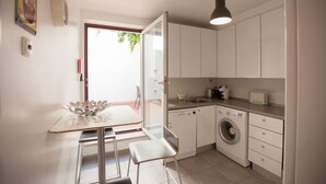 Una cocina compacta con lavadora, un lavamanos y un comedor con mesa y sillas.