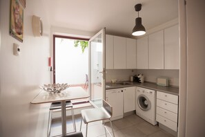 Eine kompakte Küche mit Waschmaschine, Spüle und Essbereich mit Tisch und Stühlen.