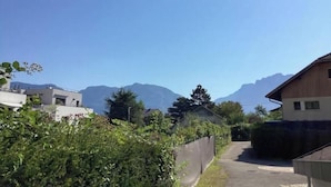 Ein Wohngebiet mit Häusern, einer schmalen Straße und Bergen im Hintergrund.