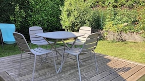 Eine Holzterrasse mit Tisch und vier Stühlen.