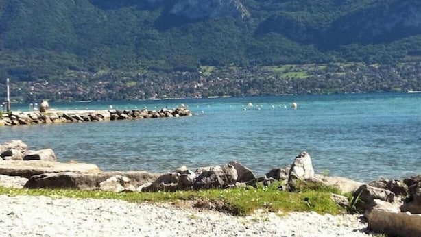 Eine Küstenlandschaft mit felsigen Ufern, klarem, blauem Wasser und Bergen im Hintergrund.