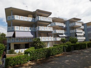 Ein mehrstöckiges Hotel mit Balkonen, einem überdachten Eingangsbereich und einem Parkplatz.