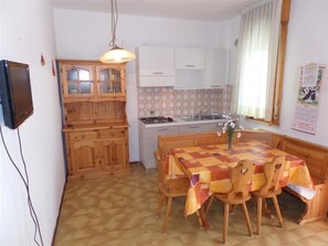 Eine kleine Küche mit Holzausstattung, einem Esstisch mit Stühlen und einer Pendelleuchte.