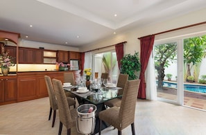 A dining area with a glass table, wicker chairs, and a view of a swimming pool. - Luxury 2BR Pool Villa Pratamnak Soi5 - 50m to Beach (Pattaya)