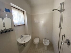Et badeværelse med vask, toilet, bidet og brusebad.