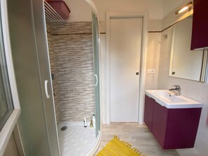 Un baño con ducha, lavamanos y espejo.