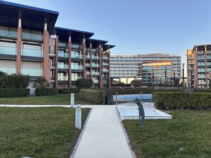 A modern multi-story building with a central courtyard, a covered walkway, and a swimming pool. - Stylish property with sea view (Lido di Jesolo)