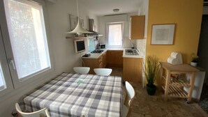 Een functionele keuken met een eethoek, een tafeltje en stoelen.