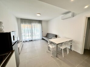 Ein moderner, minimalistischer Wohnraum mit Essbereich, einer Couch und einer Küchenzeile.
