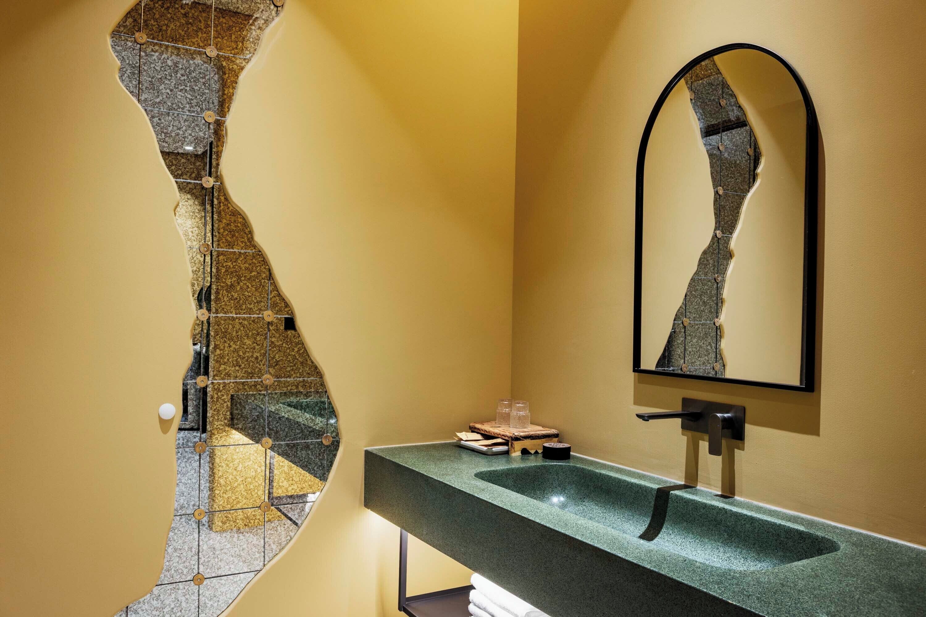 A bathroom with a unique tile design, a large mirror, and a modern sink.