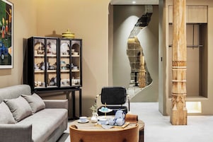 Una sala de estar moderna con un sofá, un aparador con objetos decorativos, una mesa con una bandeja de vajilla para té y una escalera espiral única.