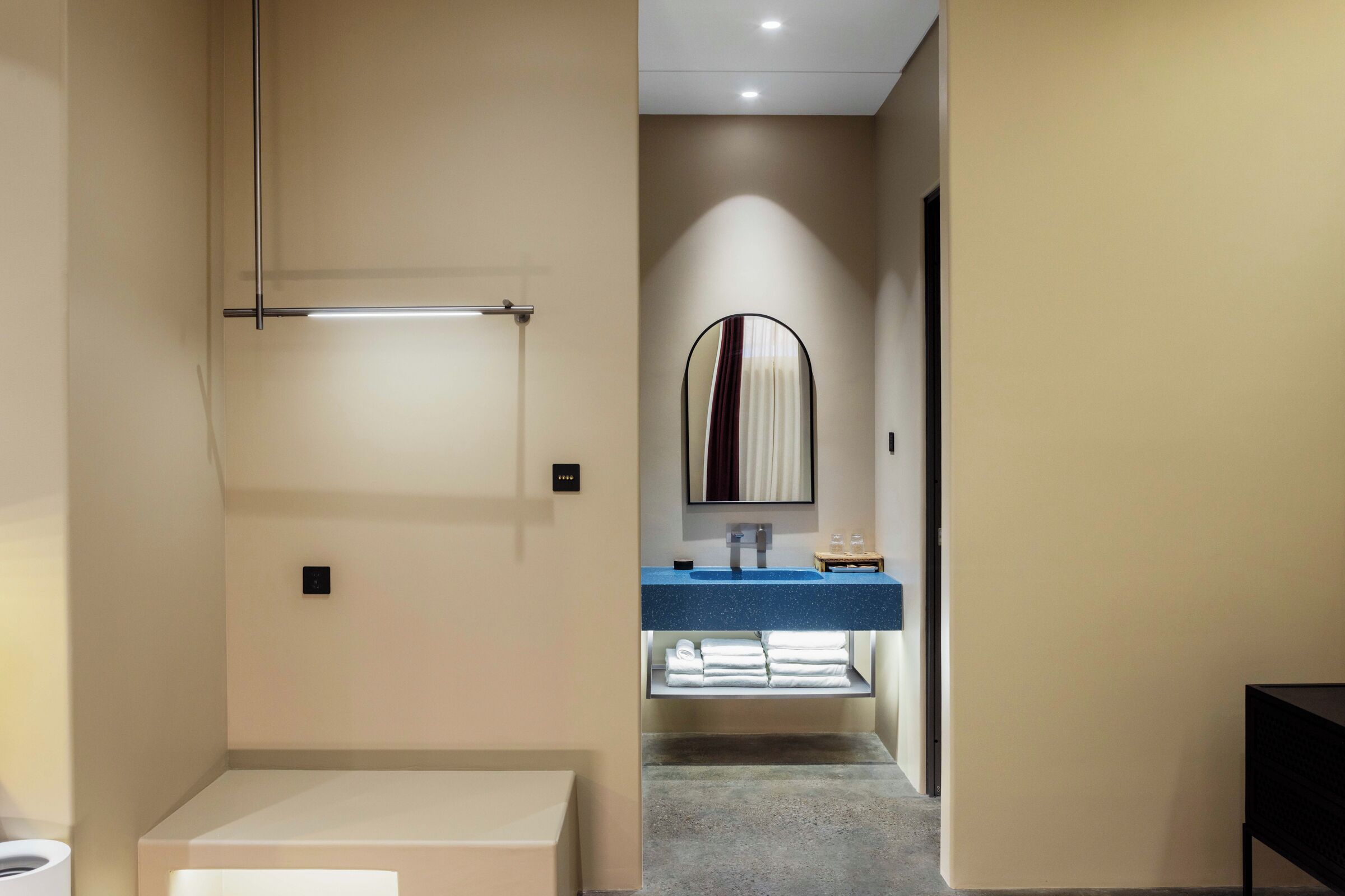 A hotel bathroom with a mirror, sink, and towel rack.