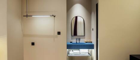 A hotel bathroom with a mirror, sink, and towel rack.