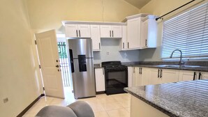 Una cocina con armarios blancos, un refrigerador de acero inoxidable, una estufa y un lavamanos.